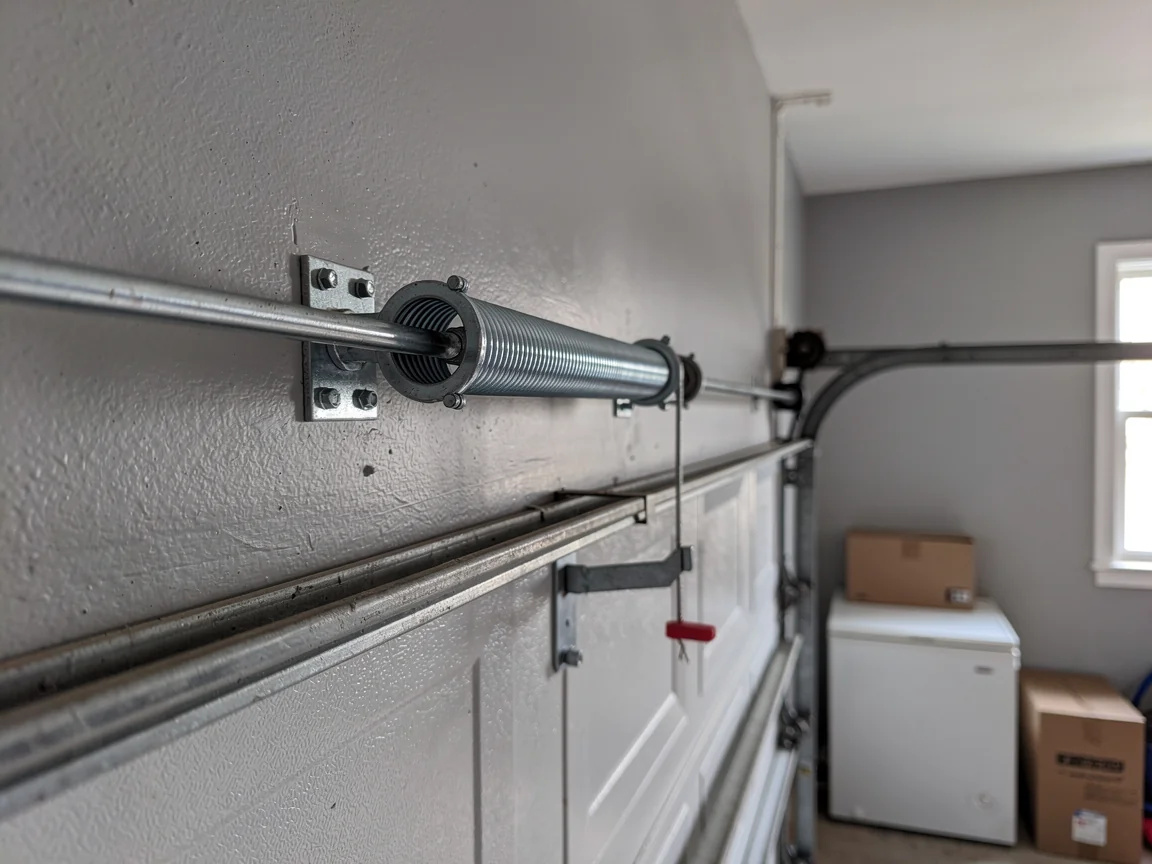 A garage door torsion spring is mounted on the wall above the door.